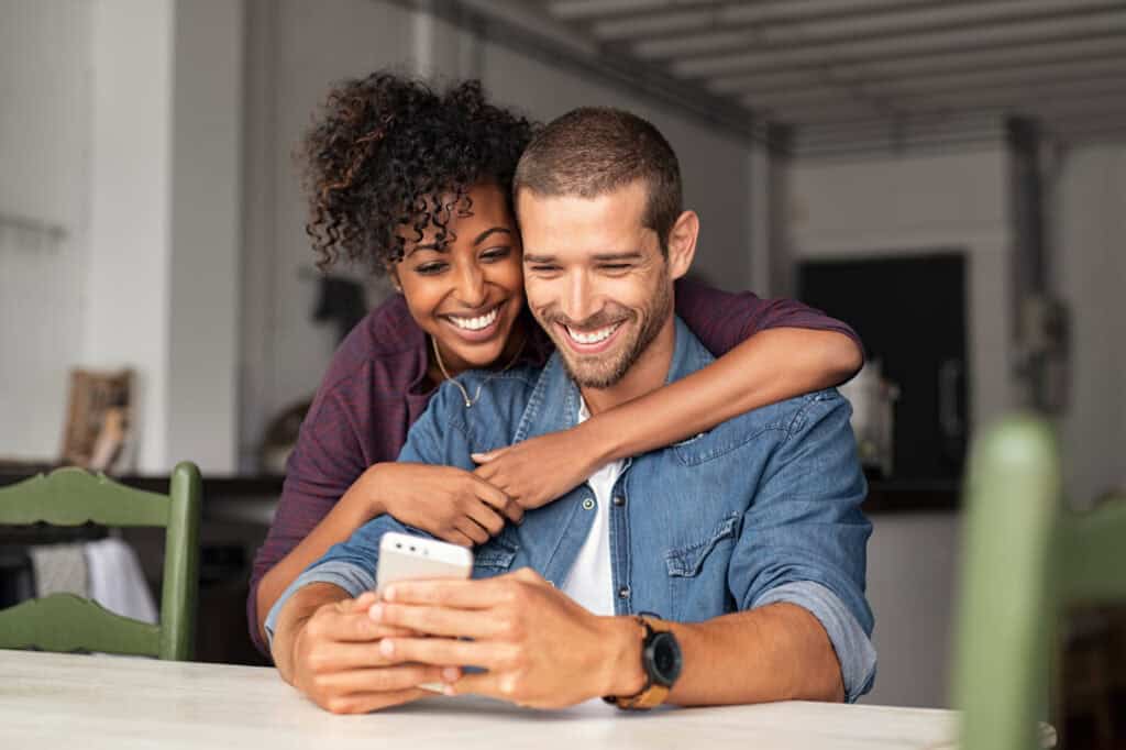 Happy couple using a VISA credit card on a smartphone at home.